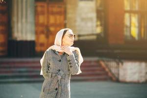 girl in a coat posing on building background photo