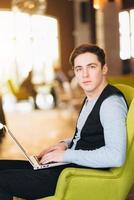 Young man with pc computer sits in a comfortable chair photo
