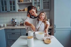 mom teaches her little daughter to cook food photo