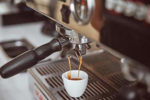 Professional espresso machine pouring fresh coffee into white ceramic cup photo