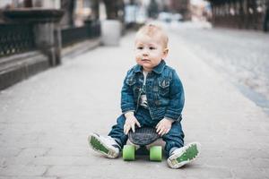 little funny boy with skateboard on the street photo