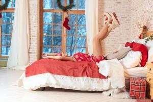 Happy young woman lying on the bed with raised legs up photo