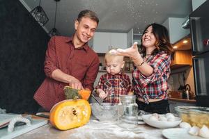 papá, mamá e hijo pequeño cocinan un pastel foto