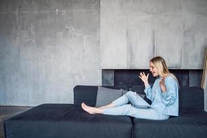 Image of happy woman using silver laptop while sitting on sofa photo