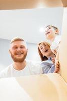 familia feliz recién mudada a una casa nueva y mirando la caja foto