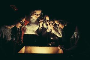 Sisters opens a box with a Christmas present and fascinated looks inside photo