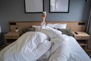 mano sosteniendo una taza de café en casa en la cama foto