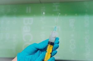 Hands in rubber gloves hold a disposable medical syringe with the drug photo