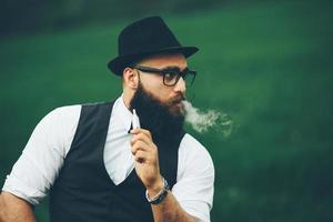 man with a beard smokes electronic cigarette photo