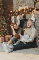 Young caucasian family mom dad son near fireplace christmas tree photo