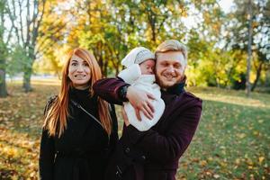 familia joven e hijo recién nacido en el parque de otoño foto