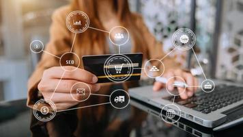 Hand using credit card and smartphone, laptop computer on wooden desk with VR icon chart graph diagram photo