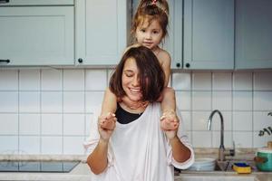 beautiful little daughter piggybacking on her happy mother photo