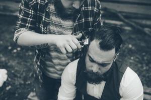barbero afeita a un hombre barbudo foto