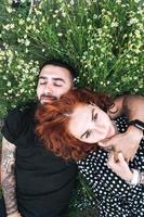 Young couple lies on the field with daisies. photo