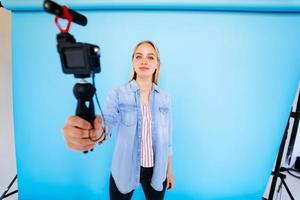 Beautiful girl blogger relieves itself at camera isolated blue background photo