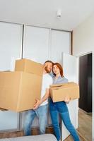 pareja feliz sosteniendo cajas de cartón y mudándose a un nuevo lugar foto
