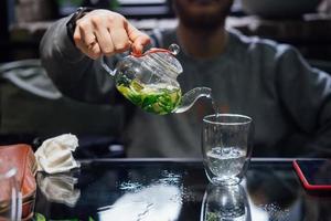 Hot green tea with mint, steam rises, dark background photo