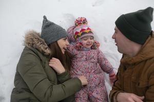 papá, mamá y su pequeña hija yacen en la nieve foto