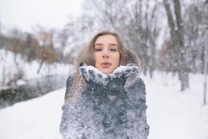 hermosa joven sopla nieve foto