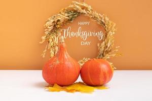 mensaje de texto feliz día de acción de gracias con colección de calabazas de otoño con corona sobre fondo naranja blanco. tarjeta de felicitación foto