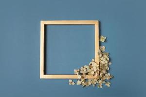 Golden square frame and dried hydrangea flowers on a green background. Vertical format. Flat lay, top view, copy space photo