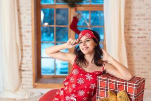 Beautiful woman in pajamas with gift box, window in the background. photo