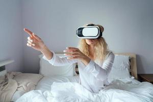 Girl sitting on a bed with VR headset photo