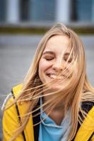 Beautiful young blonde woman on the street, posing with wind in her hair photo