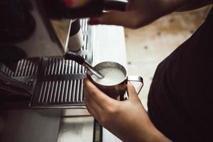 el barista está haciendo leche hervida. él usa una máquina de café especial para ello. foto