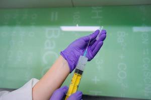 Hands in rubber gloves hold a disposable medical syringe with the drug photo