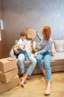 Young happy family with kid unpacking boxes together sitting on sofa photo