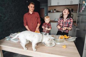 perro en la mesa de la cocina. familia feliz en la cocina foto