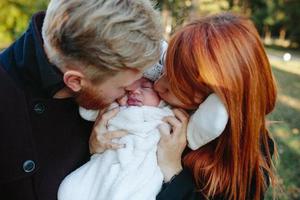 familia joven e hijo recién nacido en el parque de otoño foto