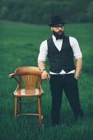 man with a beard, thinking in the field near chair photo