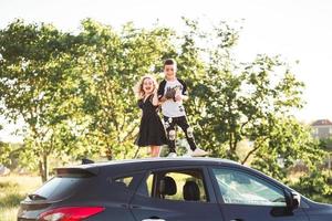 Two children stand on the roof of a car photo