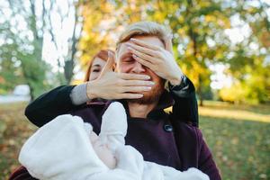 familia joven e hijo recién nacido en el parque de otoño foto