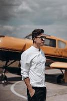 A man standing on the background of a small single engine plane. photo