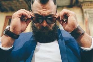 Stylish cool bearded man takes off his glasses photo