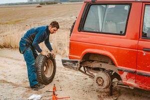 el hombre cambia la rueda manualmente en un camión todoterreno 4x4 foto