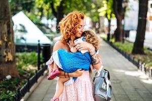 Woman hugs her daughter, holding her in her arms photo