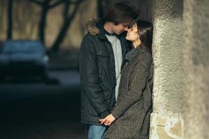 young couple standing together in front of wall photo