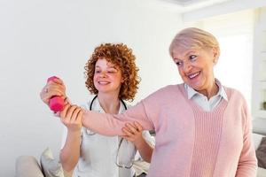 anciana después de un derrame cerebral en un hogar de ancianos haciendo ejercicio con fisioterapeuta profesional. mujer mayor que recupera la buena salud. enfermera fisioterapeuta ayudando a una anciana a rehabilitación física foto