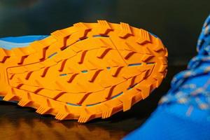 The shoes are laid out on reflective soles and a pair of blue laces are seen on the front, Orange tread soles for trail running. The sole is very thick for wading on smooth roads and muddy roads. photo