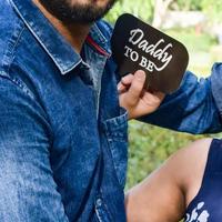 Indian couple posing for maternity baby shoot. The couple is posing in a lawn with green grass and the woman is falunting her baby bump in Lodhi Garden in New Delhi, India photo