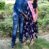 Indian couple posing for maternity baby shoot. The couple is posing in a lawn with green grass and the woman is falunting her baby bump in Lodhi Garden in New Delhi, India photo