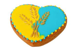 pan de jengibre en forma de corazón en colores amarillo y azul con espigas de trigo, estilo ucraniano. foto
