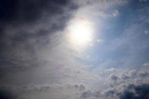 hermosa vista a los rayos de sol con algunas bengalas y nubes en un cielo azul foto