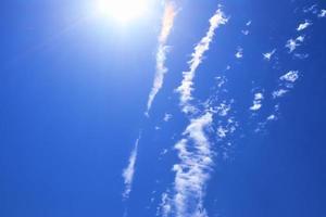 hermosa vista a los rayos de sol con algunas bengalas y nubes en un cielo azul foto