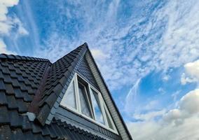 ventana de techo abierta en estilo velux con tejas negras. foto